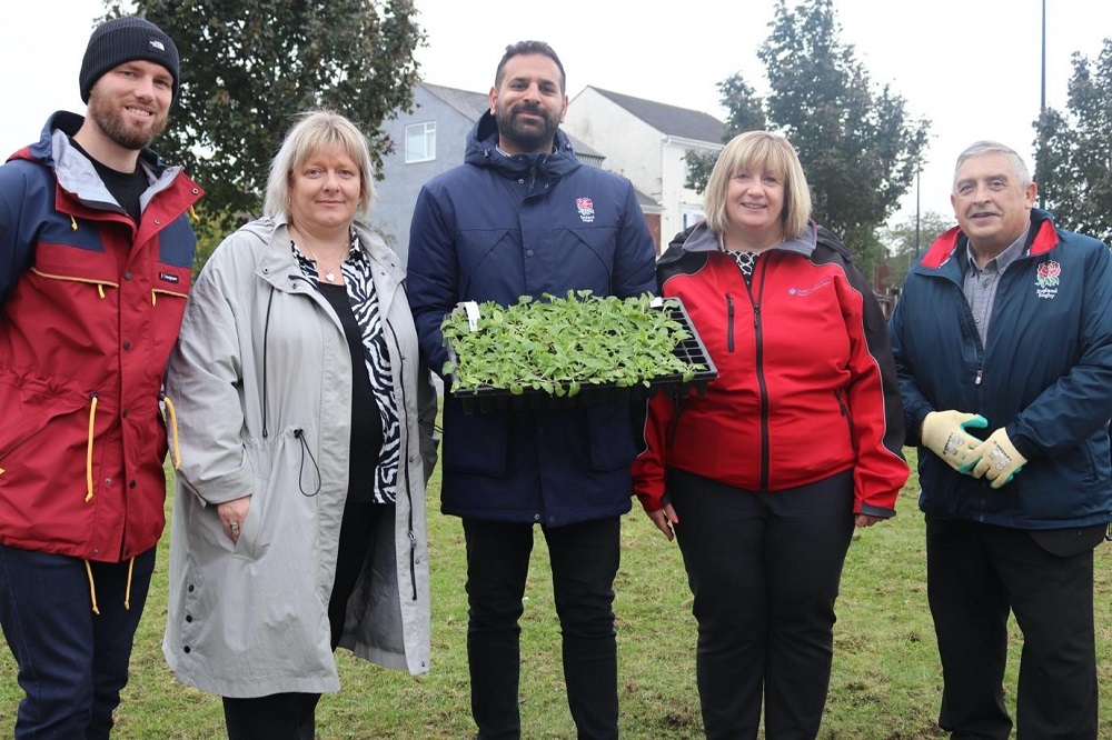 Five people having their photo taken, with one holding a tray of bulbs to plant