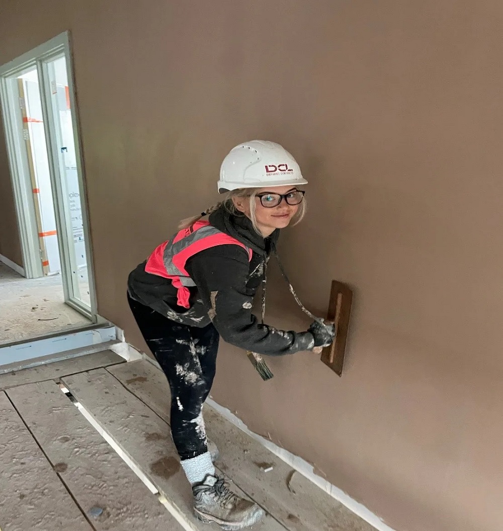 Photo of Paige plastering a wall